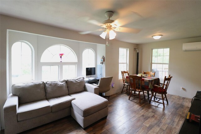 living room with dark wood-style floors, a wall unit AC, and a ceiling fan
