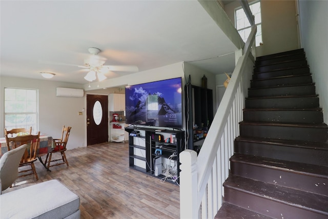 staircase with a wall mounted AC, wood finished floors, and a ceiling fan