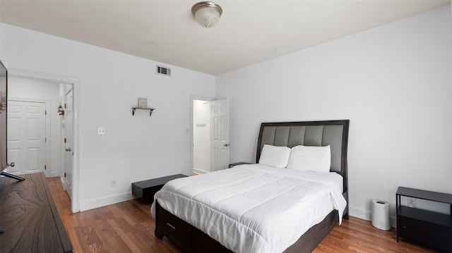 bedroom featuring wood finished floors, baseboards, and visible vents