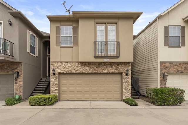 multi unit property with stone siding, an attached garage, and concrete driveway