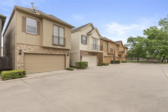view of front facade with stone siding, concrete driveway, stucco siding, fence, and an attached garage