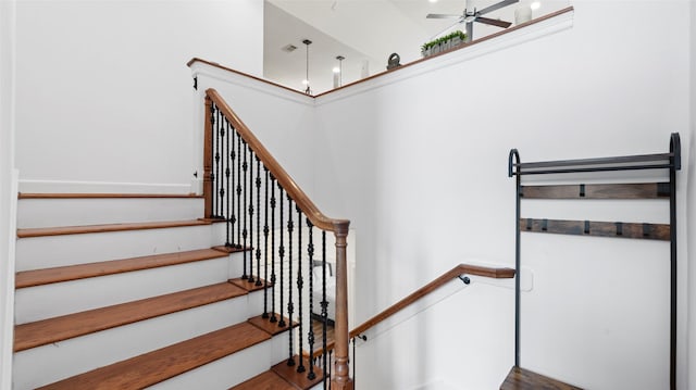 stairway featuring a high ceiling, wood finished floors, and ceiling fan