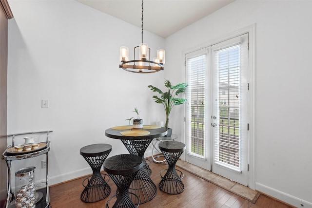 dining area featuring a healthy amount of sunlight, baseboards, hardwood / wood-style flooring, and a chandelier