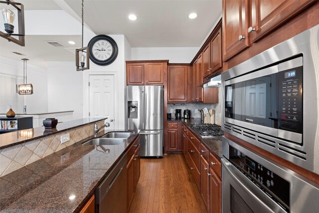 kitchen featuring a sink, tasteful backsplash, dark wood finished floors, stainless steel appliances, and visible vents