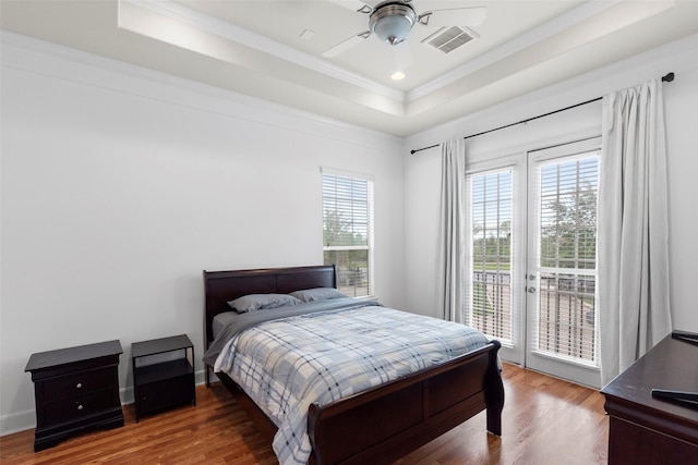bedroom featuring a raised ceiling, wood finished floors, access to outside, and visible vents