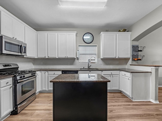 13923 Roanoke Falls Dr, Cypress, TX 77429 - kitchen with appliances with stainless steel finishes, a sink, a peninsula, a kitchen island, and white cabinetry