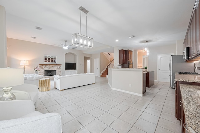 1218 Ventura Canyon Dr, Katy, TX 77494 - living area with ceiling fan, visible vents, a stone fireplace, stairway, and light tile patterned flooring