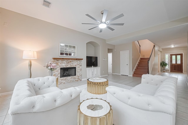 1218 Ventura Canyon Dr, Katy, TX 77494 - living area with light tile patterned floors, a ceiling fan, a stone fireplace, visible vents, and stairway