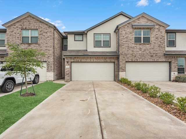 townhome / multi-family property with stucco siding, an attached garage, driveway, and brick siding