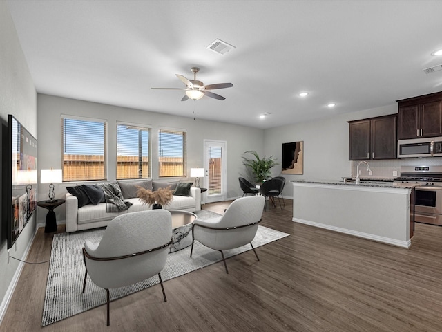 living area with ceiling fan, baseboards, wood finished floors, and visible vents