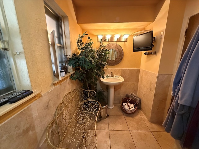 bathroom featuring tile walls, tile patterned floors, a wainscoted wall, and a sink