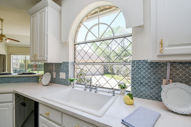 kitchen featuring black dishwasher, a sink, light countertops, and decorative backsplash