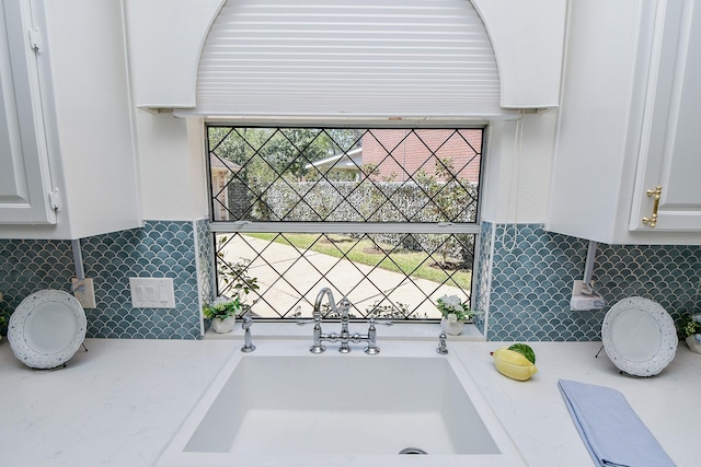 kitchen view of white cabinetry, decorative backsplash, and light stone countertops