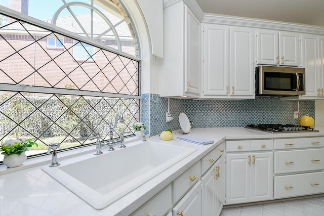 kitchen with stainless steel appliances, light countertops, white cabinets, and a sink