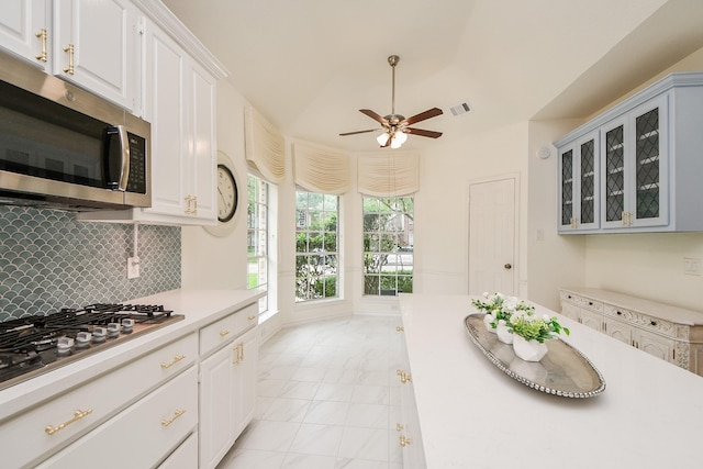 kitchen with stainless steel appliances, light countertops, a ceiling fan, and white cabinets