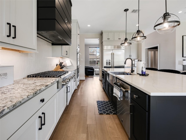 10114 Mariner Oaks Dr, Missouri City, TX 77459 - kitchen featuring backsplash, a sink, light wood-style flooring, appliances with stainless steel finishes, and custom exhaust hood