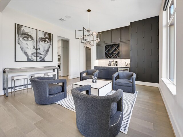 10114 Mariner Oaks Dr, Missouri City, TX 77459 - living area featuring light wood-type flooring, an inviting chandelier, baseboards, a dry bar, and visible vents