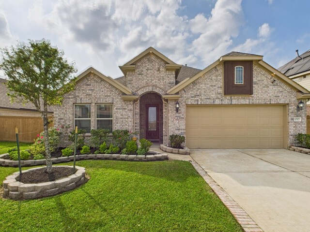 view of front of house with driveway, fence, an attached garage, brick siding, and a front lawn