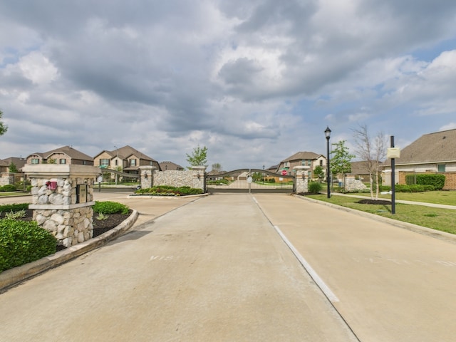 12527 Sabine Point Dr, Humble, TX 77346 - view of concrete street with a residential view, street lights, a gate, curbs, and a gated entry