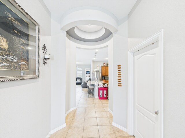 corridor with light tile patterned flooring and baseboards