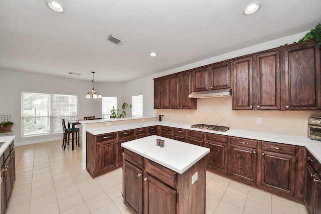313 Overlook Dr, Friendswood, TX 77546 - kitchen featuring a wealth of natural light, stainless steel gas cooktop, light countertops, tasteful backsplash, and under cabinet range hood