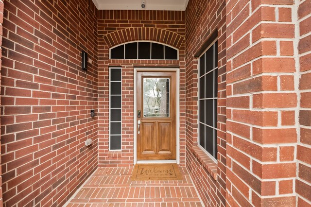 doorway to property featuring brick siding