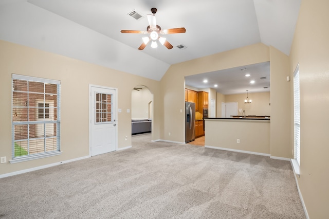 unfurnished living room with a ceiling fan, visible vents, lofted ceiling, and light carpet