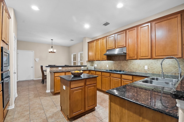 kitchen featuring a sink, under cabinet range hood, visible vents, a peninsula, and appliances with stainless steel finishes