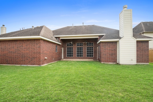 rear view of house with a lawn, brick siding, and a chimney