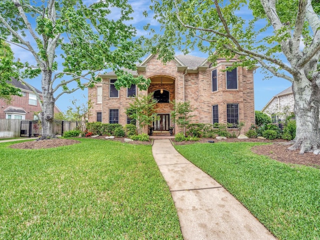 traditional-style home with a front yard, fence, and brick siding