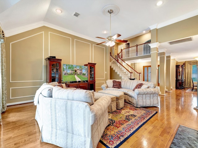 living room featuring visible vents, light wood-style flooring, a decorative wall, and a ceiling fan