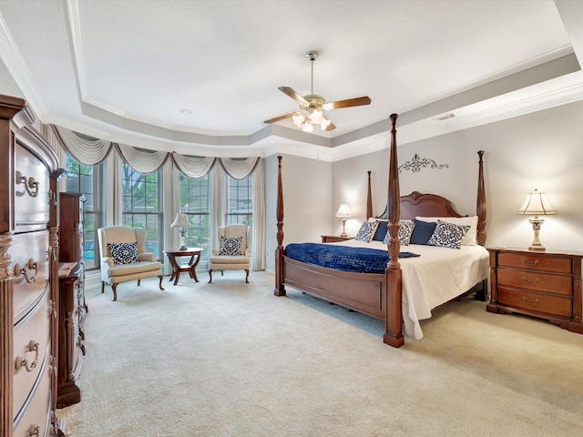carpeted bedroom with a tray ceiling, ceiling fan, and ornamental molding
