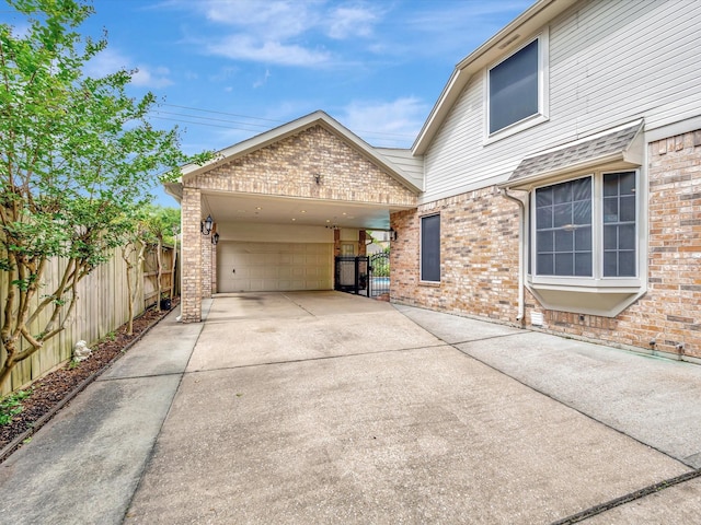 view of side of property with driveway, an attached garage, fence, and brick siding