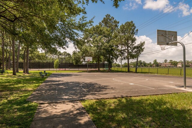 view of basketball court featuring a lawn, community basketball court, and fence