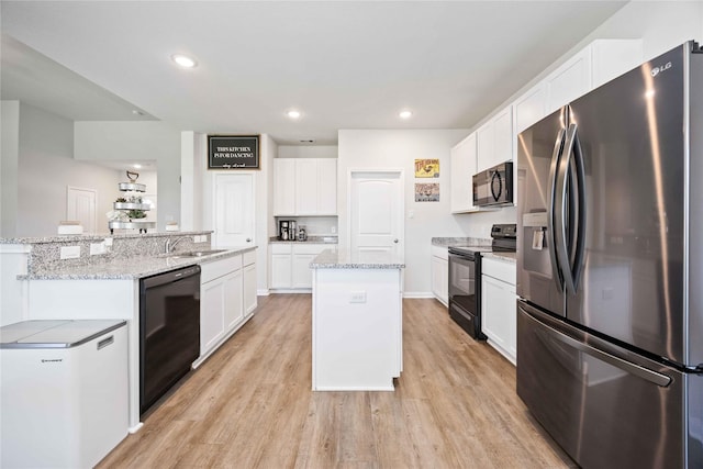 212 Bryan Way, Angleton, TX 77515 - kitchen featuring an island with sink, light wood-style flooring, white cabinetry, black appliances, and a sink