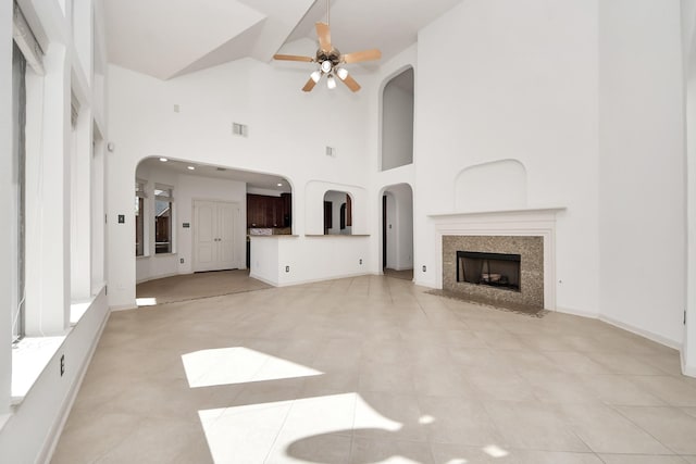 6423 Middlelake Ct, Katy, TX 77450 - unfurnished living room with arched walkways, ceiling fan, a fireplace, visible vents, and a towering ceiling