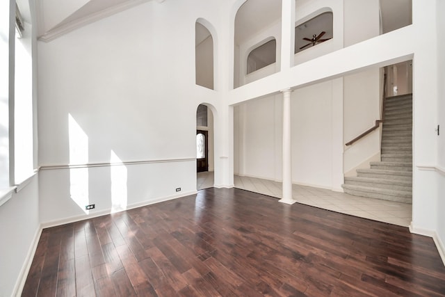 6423 Middlelake Ct, Katy, TX 77450 - unfurnished living room with wood finished floors, arched walkways, baseboards, stairs, and a high ceiling