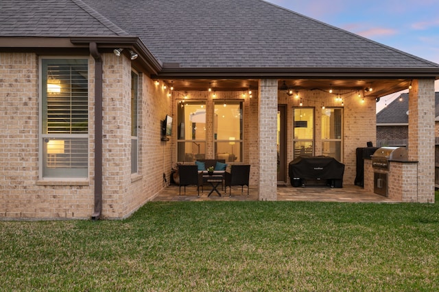 19843 Quarry Stone Ln, Richmond, TX 77407 - back of house with an outdoor kitchen, a patio, brick siding, and a yard