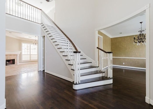 4135 Bellefontaine, Houston, TX 77025 - stairs featuring a chandelier, wood finished floors, baseboards, a high ceiling, and a tiled fireplace