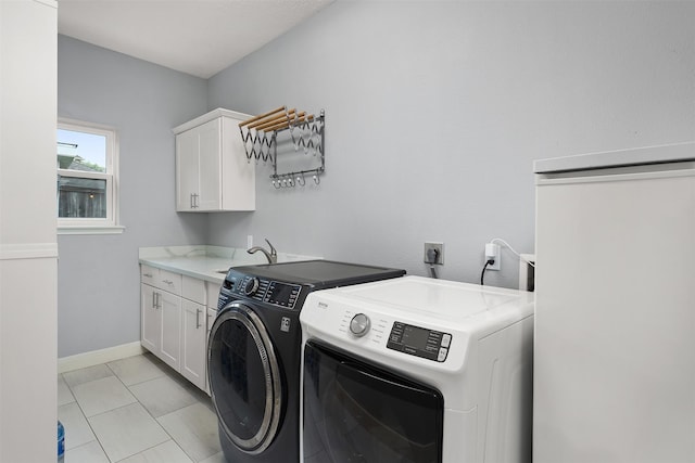 clothes washing area featuring washer and clothes dryer, baseboards, a sink, light tile patterned flooring, and cabinet space