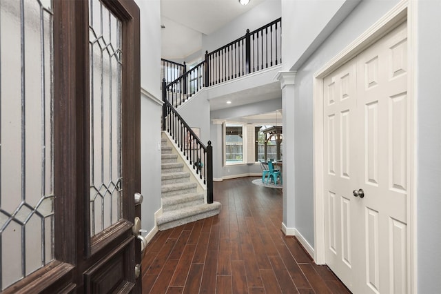 entryway featuring baseboards, a towering ceiling, wood finished floors, and stairway