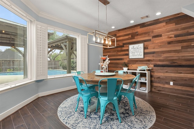 dining space with a notable chandelier, wood walls, dark wood-style floors, baseboards, and visible vents