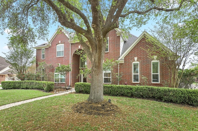 traditional-style house featuring brick siding, a chimney, and a front yard
