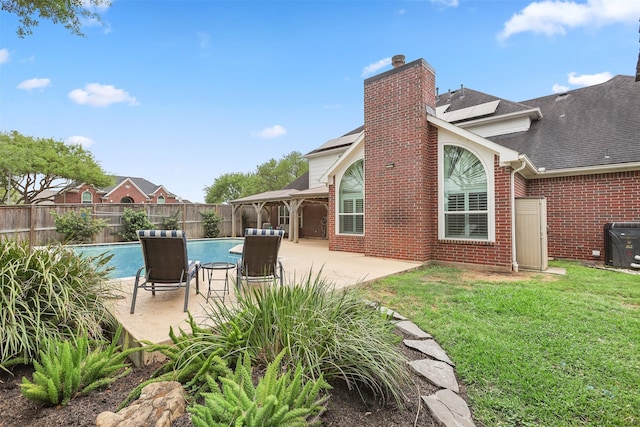 back of house with roof mounted solar panels, a fenced in pool, a fenced backyard, a lawn, and a patio area