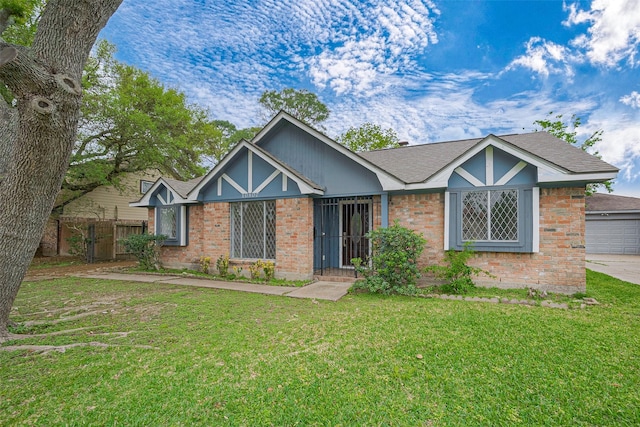 view of front of property with brick siding, a front yard, a shingled roof, and fence