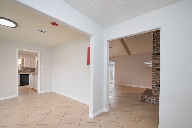 spare room featuring baseboards, a textured ceiling, visible vents, and light tile patterned floors