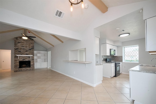 kitchen featuring stainless steel microwave, range with gas stovetop, a sink, ceiling fan, and visible vents
