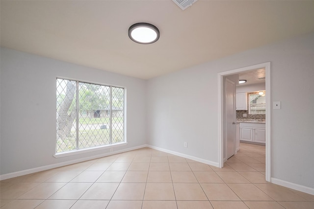 unfurnished room with baseboards, visible vents, and light tile patterned floors