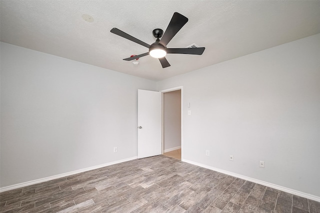spare room featuring wood finished floors, a textured ceiling, baseboards, and ceiling fan