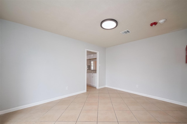 unfurnished room with baseboards, visible vents, and light tile patterned floors